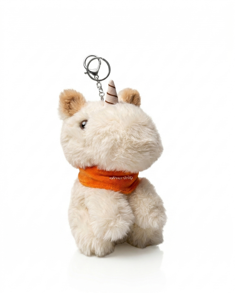 Plush unicorn keychain with an orange bandana on a white background